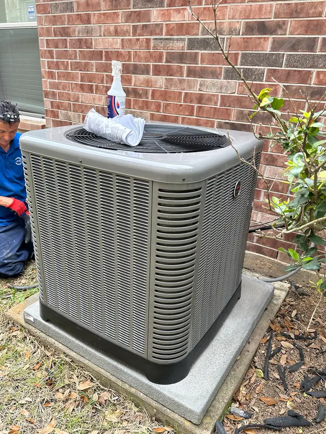 Air Oracle technician in a branded polo working on a Rheem outdoor unit