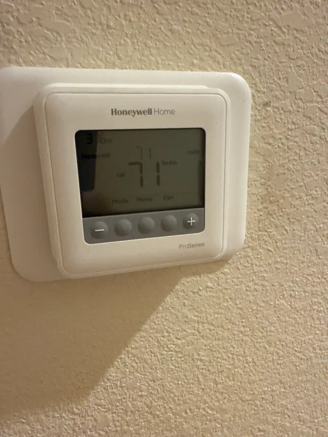 Honeywell Home ProSeries thermostat on a living room wall reading 71 degrees