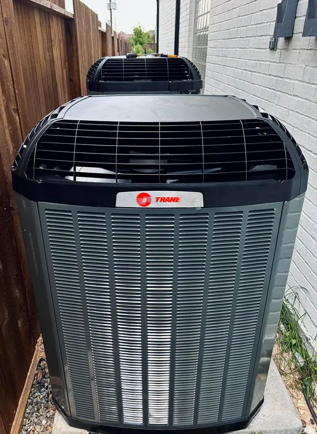 Two new Trane XV condensers side by side beside a brick house in Cypress
